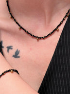 Black beaded necklace and bracelet layered with other jewelry