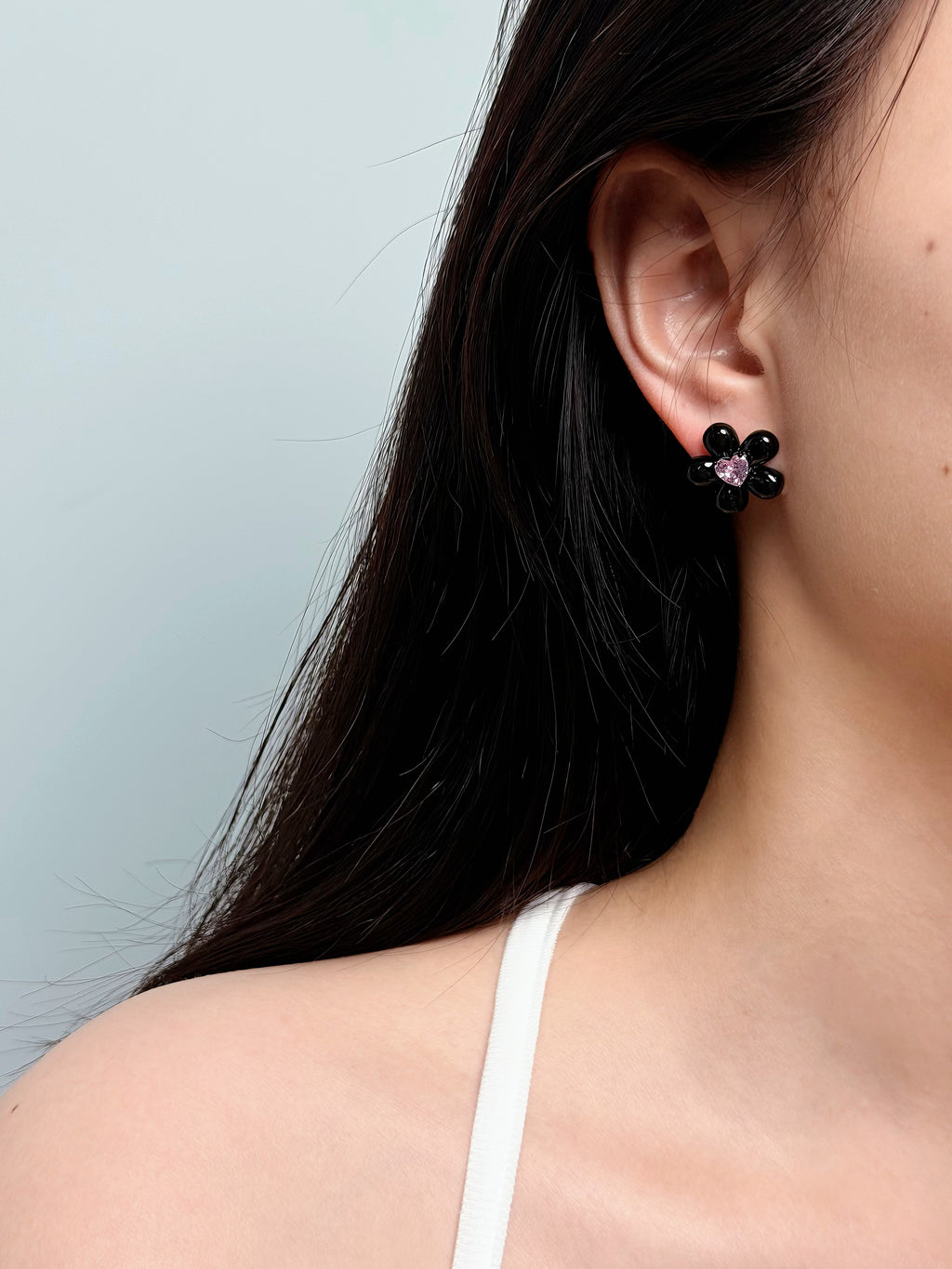 woman wearing black flower stud earrings