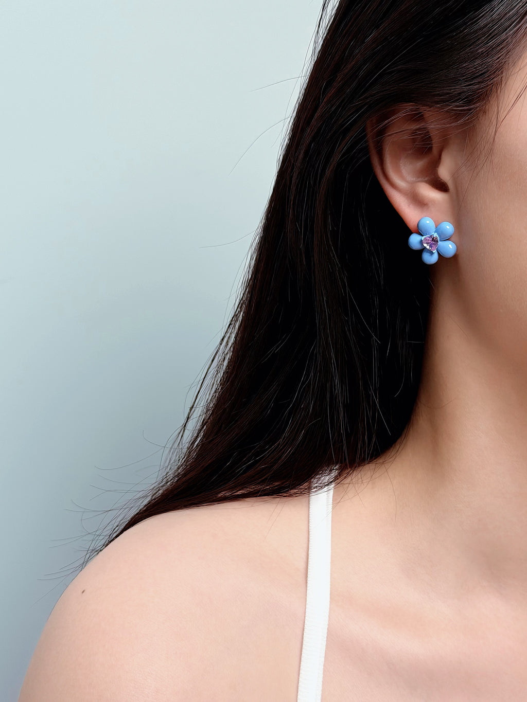 woman wearing blue flower stud earrings