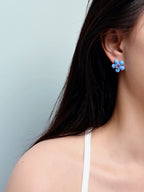 woman wearing blue flower stud earrings