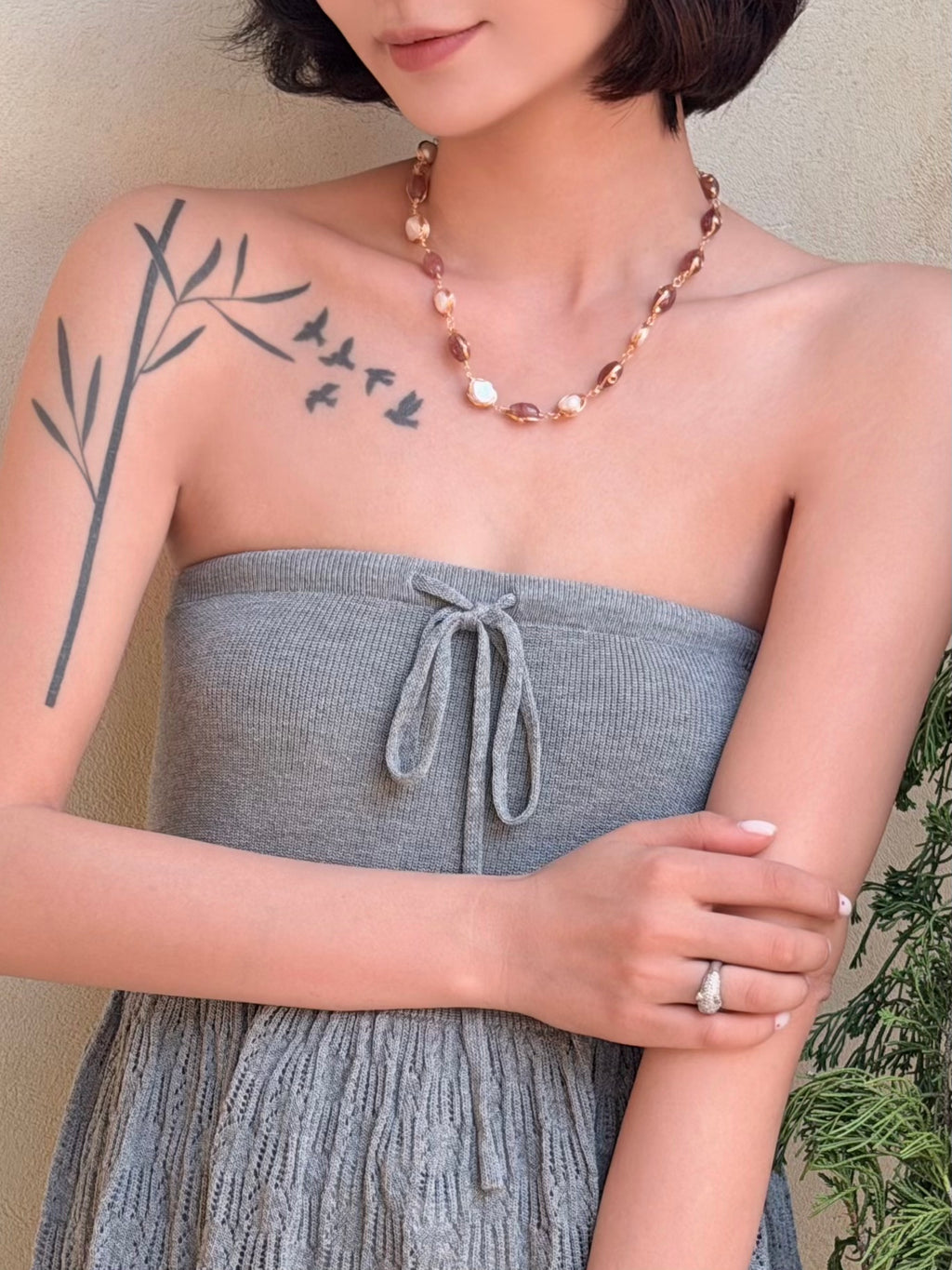 Brown red beaded pearl necklace worn around the neckline