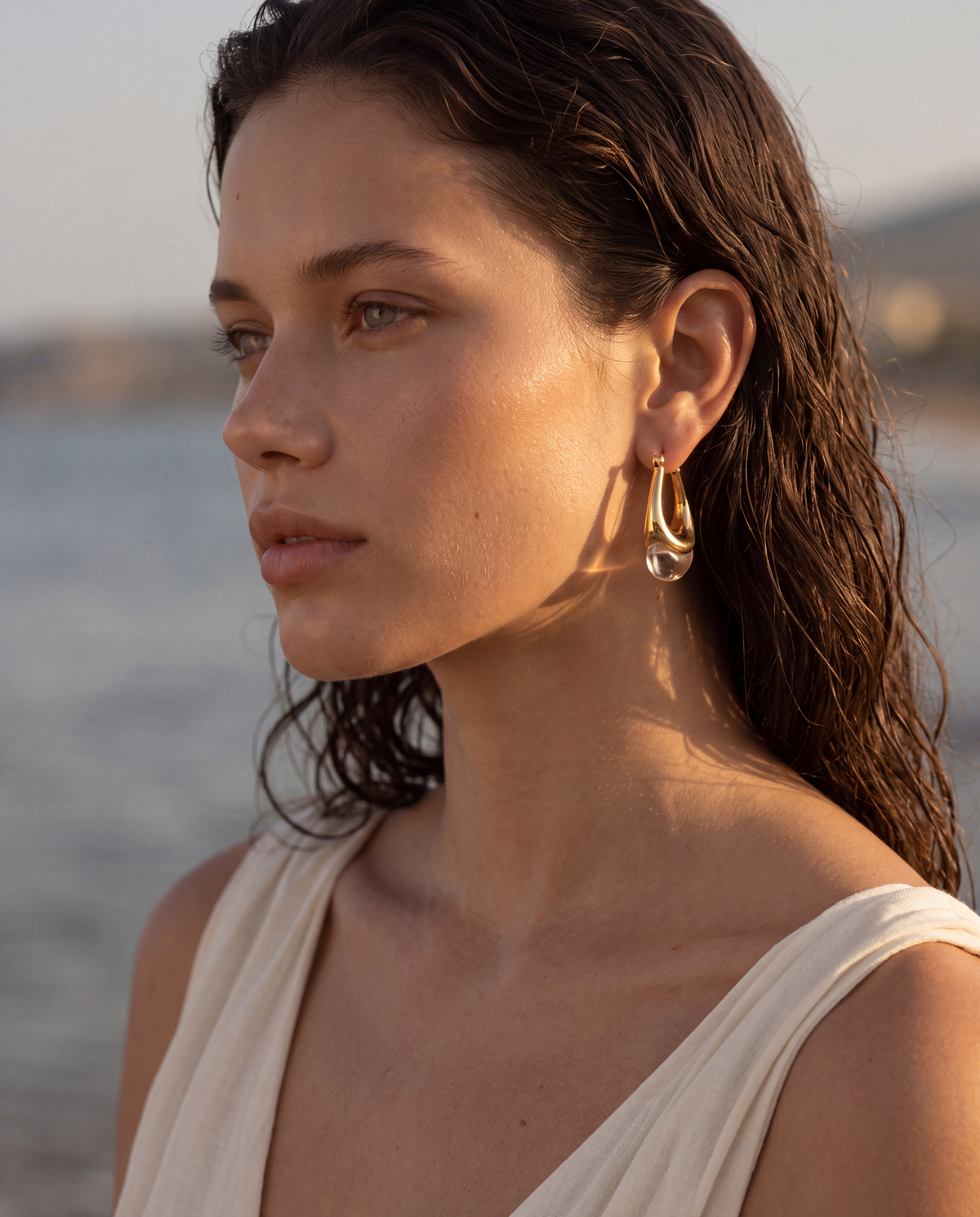 woman wearing gold crystal teardrop earrings