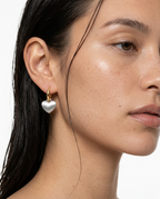 woman wearing gold heart pendant earrings