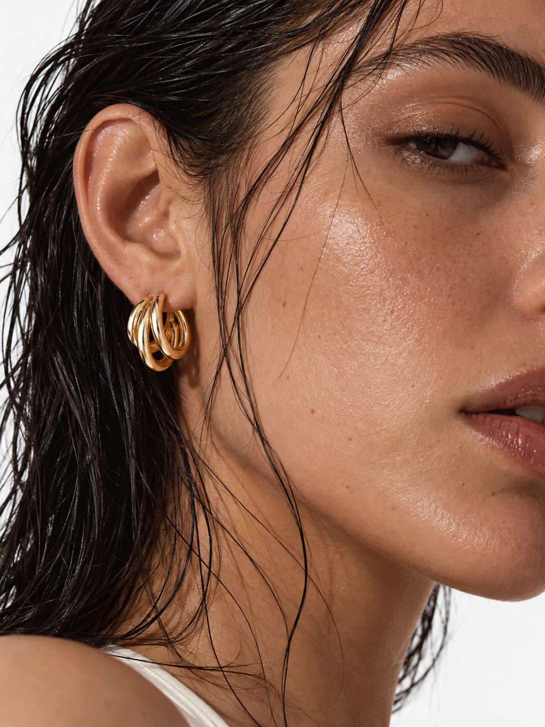 woman wearing gold sculptural hoop earrings