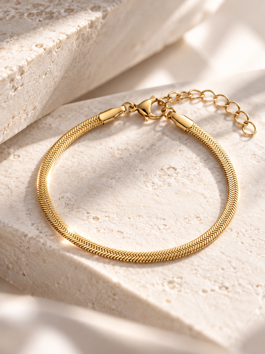 Gold-tone snake chain bracelet layered with other bracelets