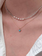Gray crystal pearl necklace layered with gold chains
