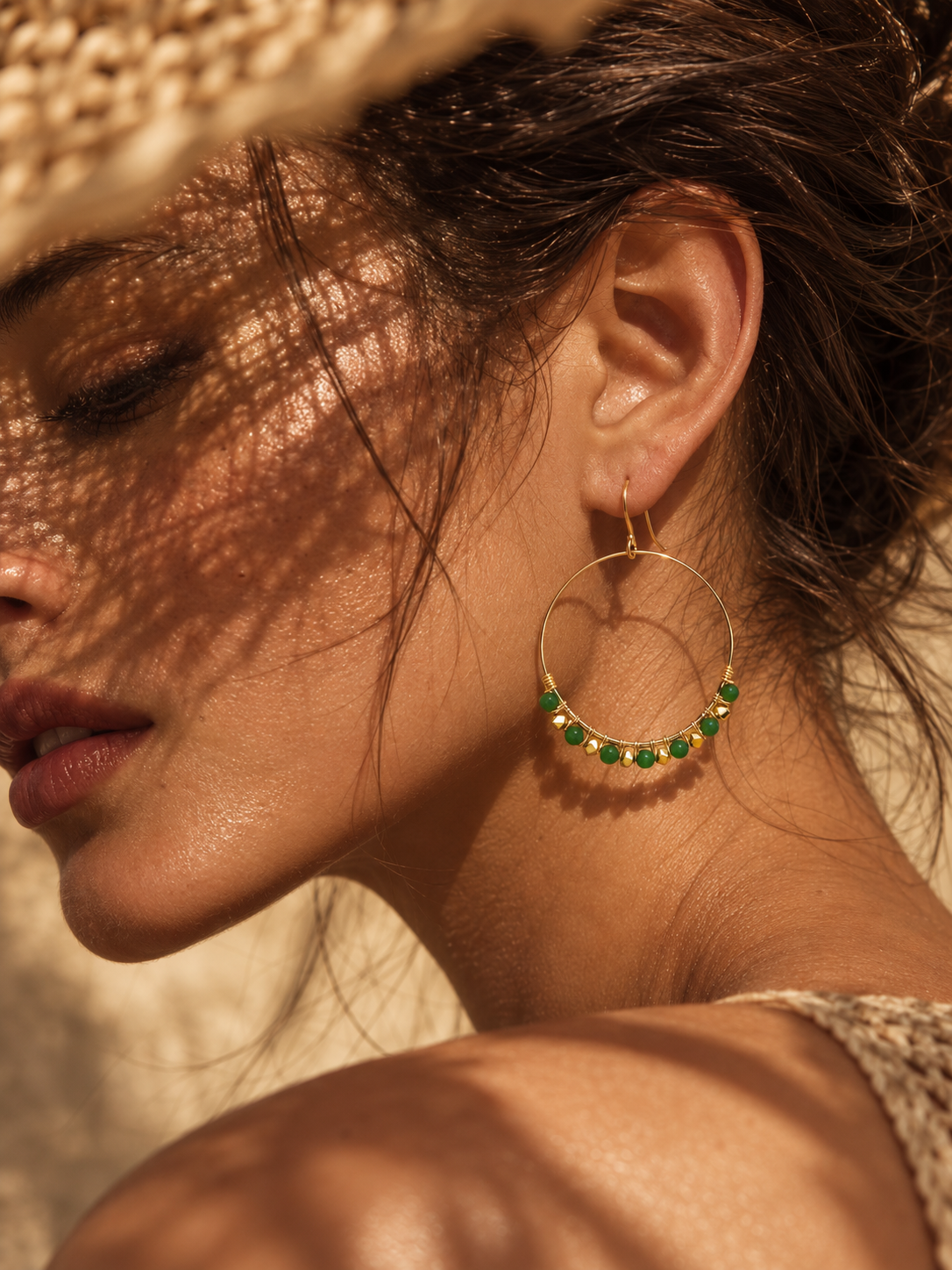 woman wearing green gemstone hoop earrings