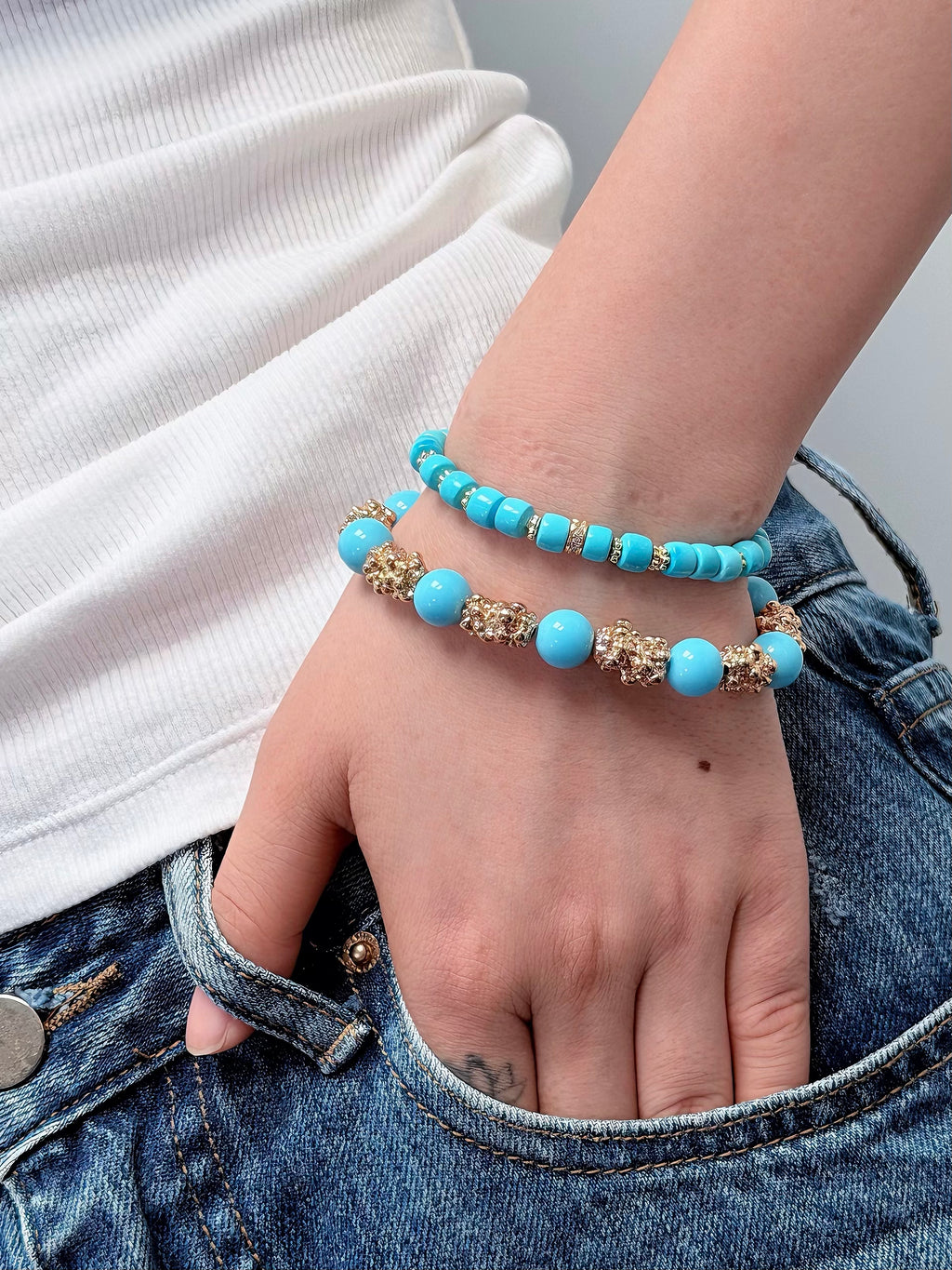Imitation turquoise beaded bracelet layered with other bracelets