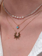 Blue heart necklace layered with delicate gold chains
