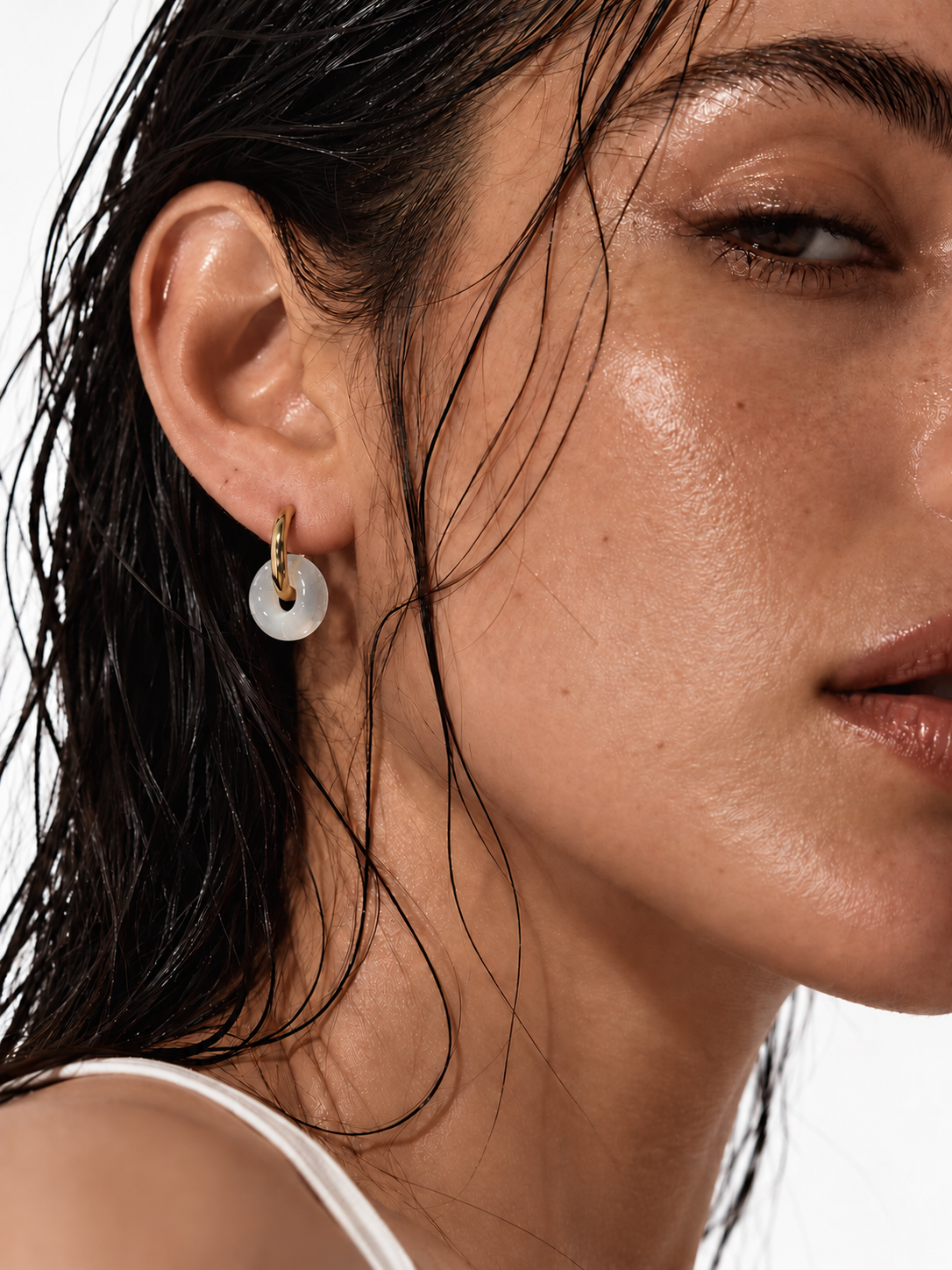 Woman wearing minimalist gold hoop earrings with geometric pendant