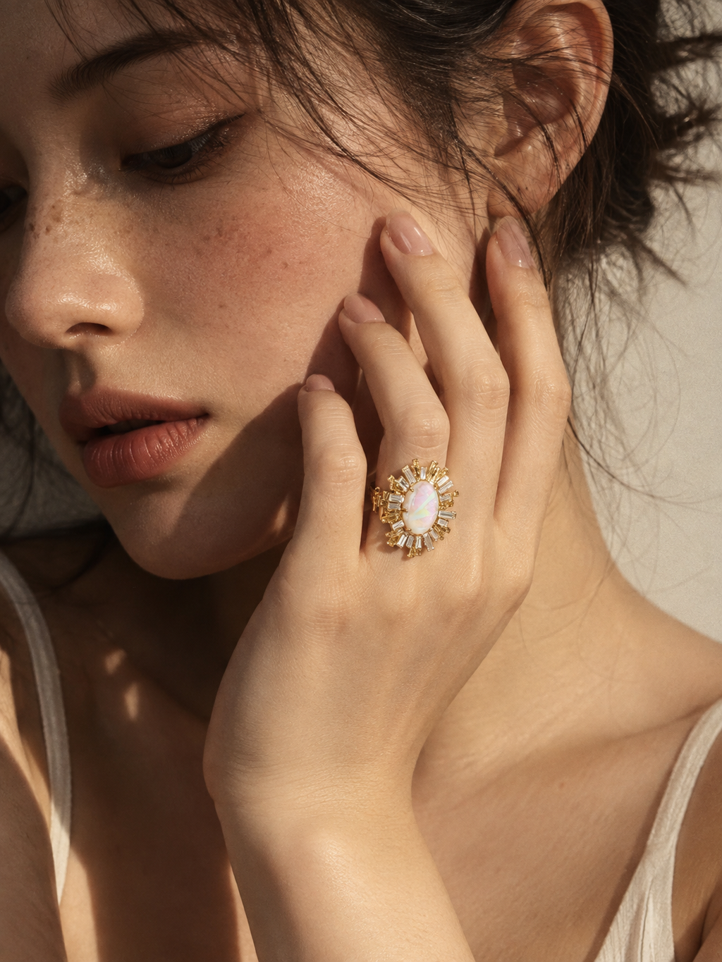 Opal-effect sunburst ring worn on finger