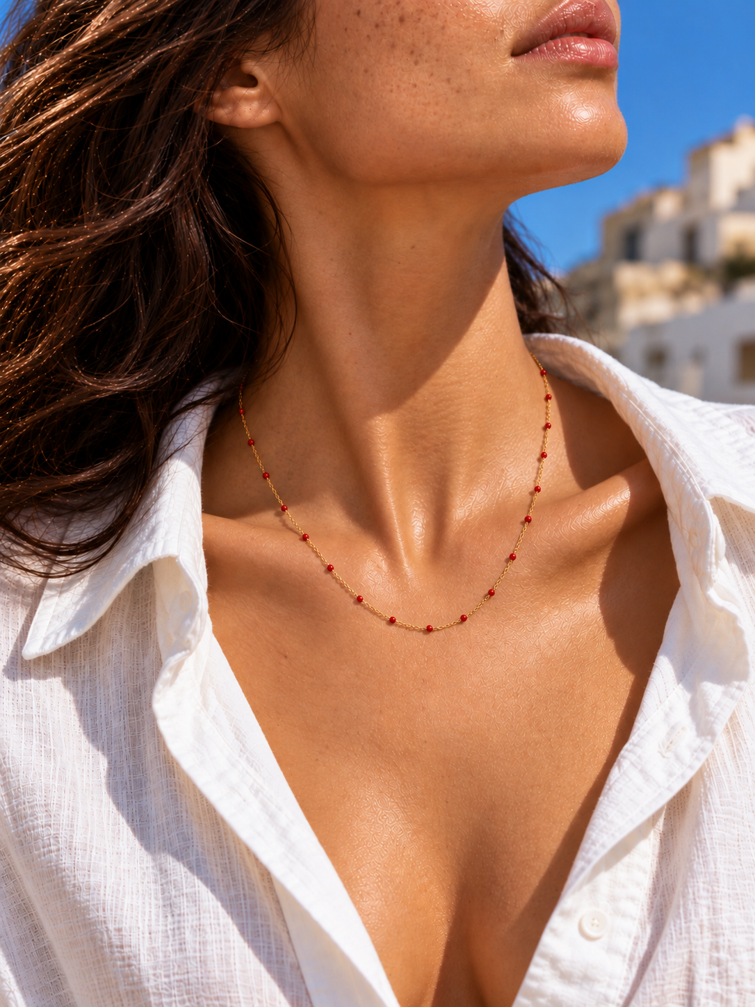 Red enamel gold necklace worn around the collarbon