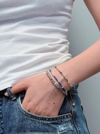 Silver metal bracelet layered with other bracelets