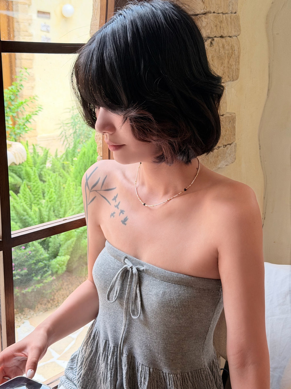 White and gold beaded necklace worn around the neckline