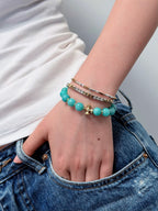 Woman wearing natural amazonite beaded bracelet with gold cross
