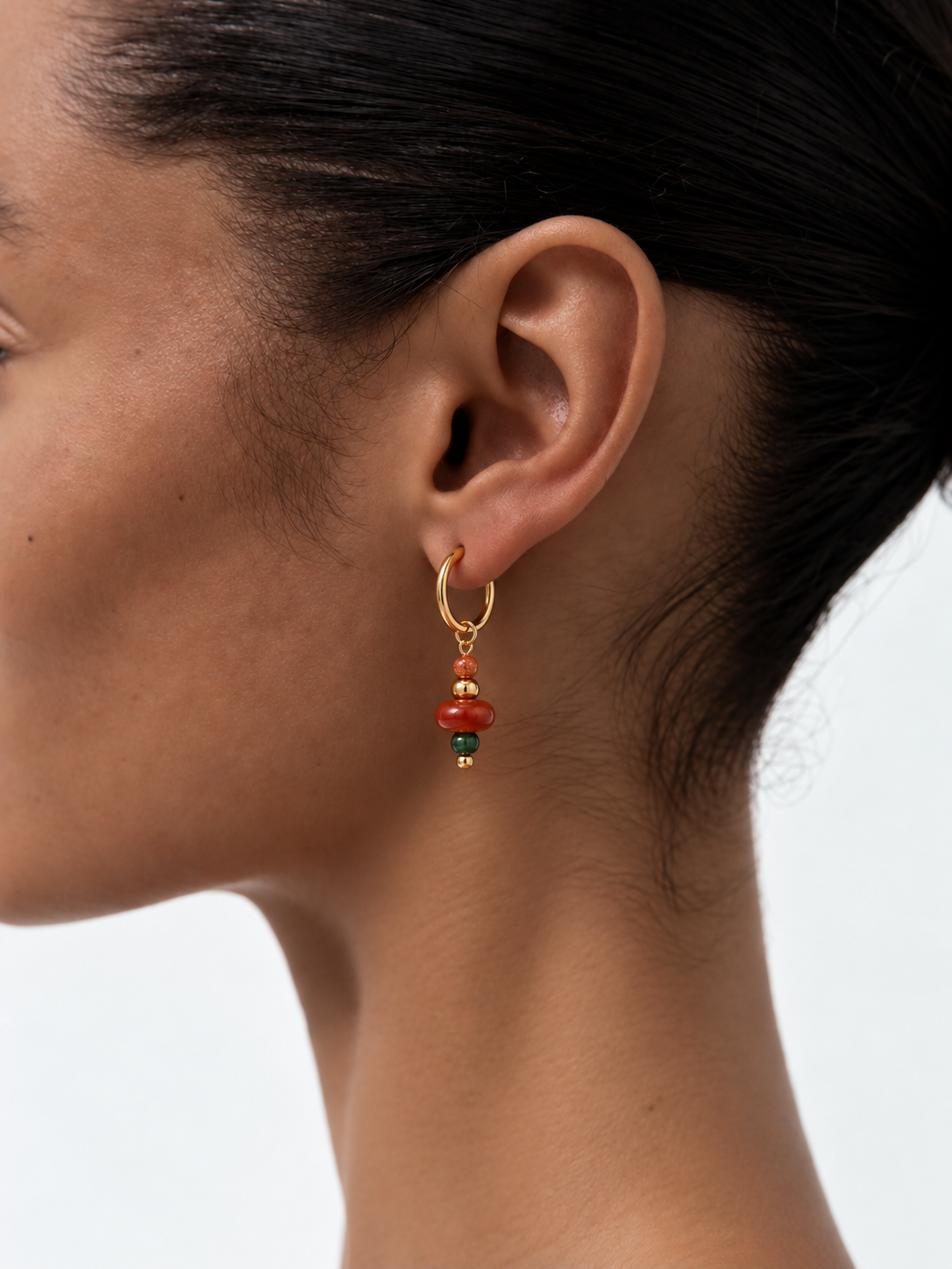 Woman wearing handmade red and green stone pendant earrings